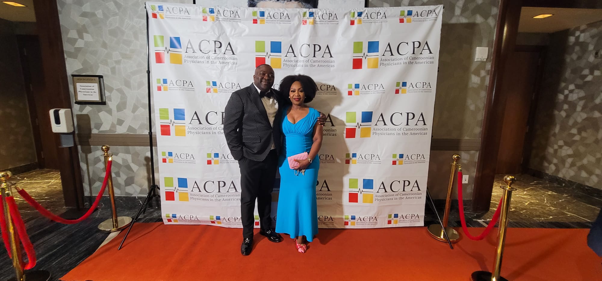 Panel discussion with four professionals seated behind a long black table; one woman speaks into a microphone while others listen, in a conference room setting with a cup of coffee on the table.